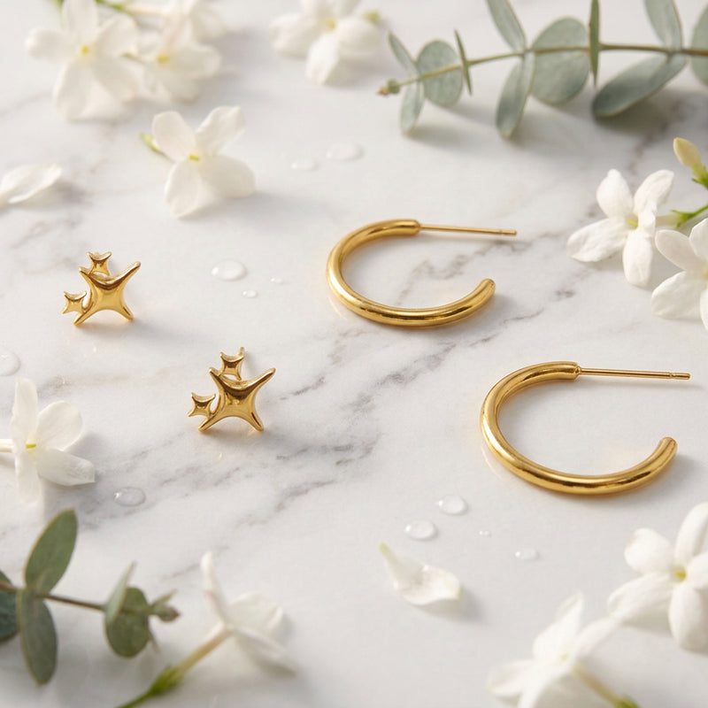 Gold star-shaped earrings and hoop earrings on a light gray background
