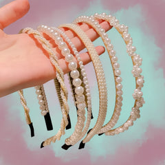 Hand holding five pearl-decorated headbands arranged side by side, featuring assorted pearl sizes and patterns against a pastel pink and teal gradient background.