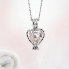 Elegant silver heart-shaped cage necklace featuring a pink pearl pendant displayed on a soft pastel background.