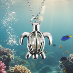 Elegant silver turtle-shaped pendant necklace featuring a central pearl displayed against an underwater coral scene.