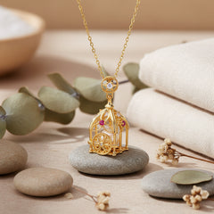 A gold-toned necklace with an intricate carriage-shaped pendant, featuring a white pearl window, small pink gemstone accents, and a star-shaped clear stone on the ring clasp, displayed on a light tan textured surface.