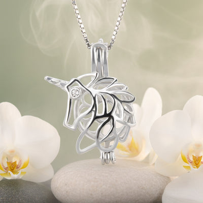 A sterling silver unicorn pearl cage pendant with a delicate chain, shown in front of white orchids and white stones background.