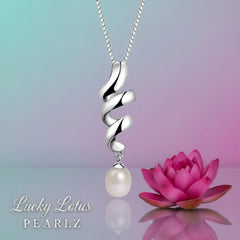 Sterling silver twisted ribbon pendant with an 8mm white freshwater pearl displayed beside a pink lotus flower on a reflective surface.