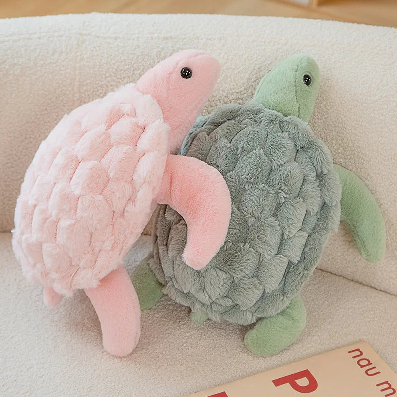 Two plush turtle toys, one pink and one green, on a beige surface.