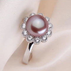 Sterling silver ring featuring a purple freshwater pearl with a sparkling gemstone flower halo on a soft fabric background.