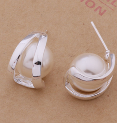 White pearl earrings with curved silver-tone settings, one turned to reveal its straight post.